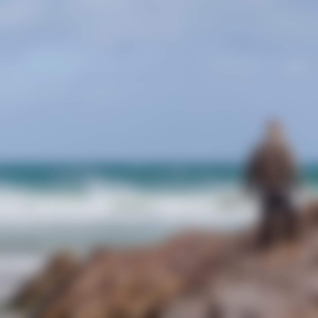 Mallacoota beach man standing on rocks with waves in background