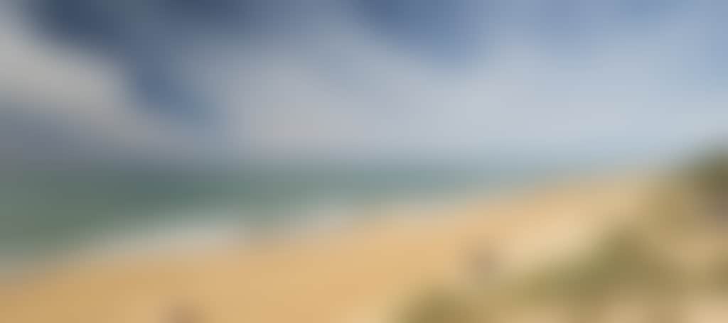 Ninety Mile Beach couple and fisherman walking along beach on sunny day