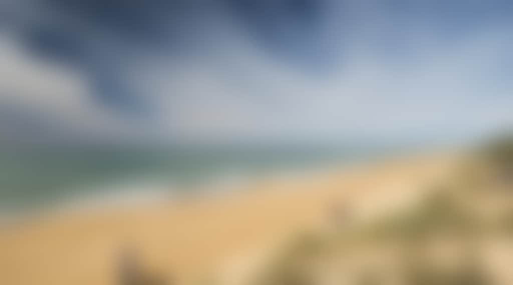 Ninety Mile Beach couple and fisherman walking along beach on sunny day
