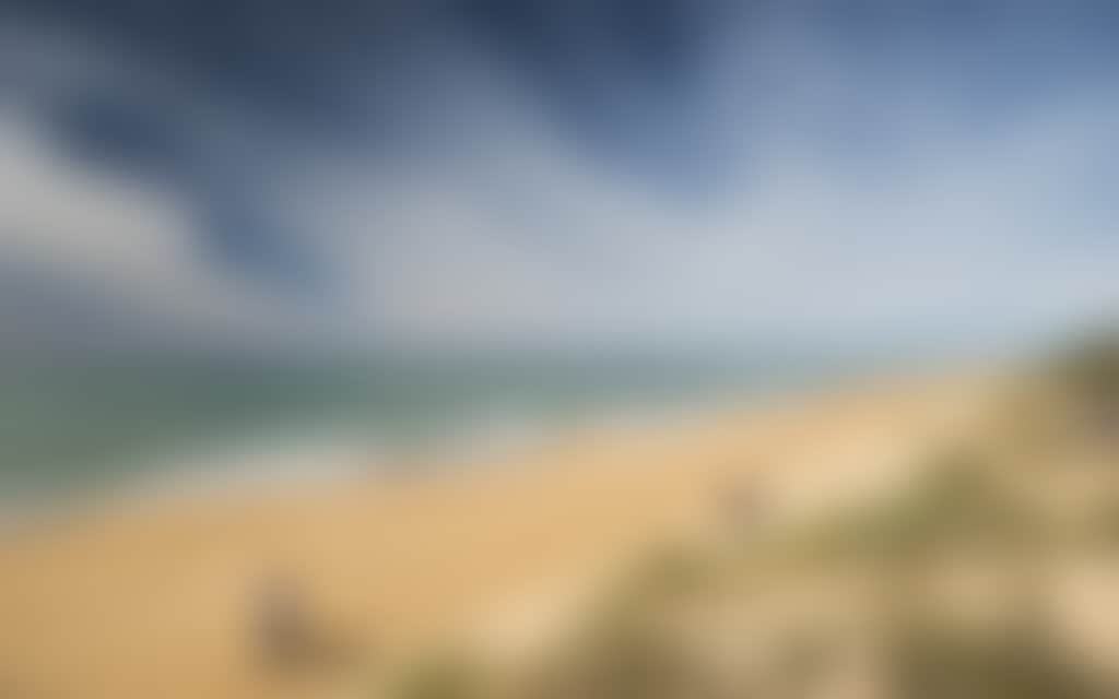 Ninety Mile Beach couple and fisherman walking along beach on sunny day
