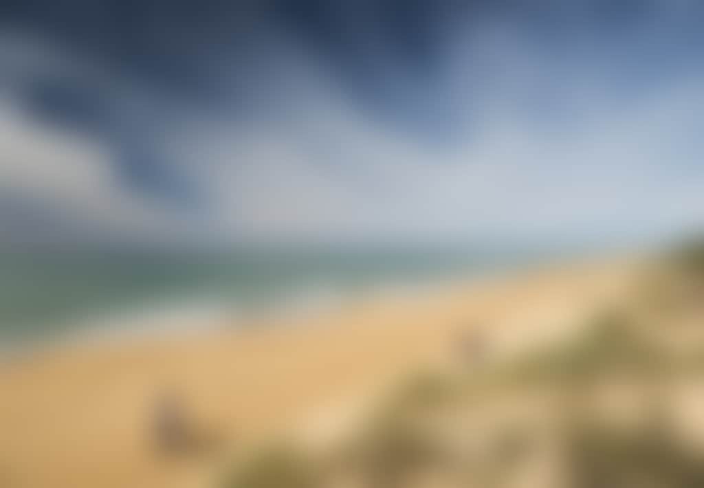 Ninety Mile Beach couple and fisherman walking along beach on sunny day