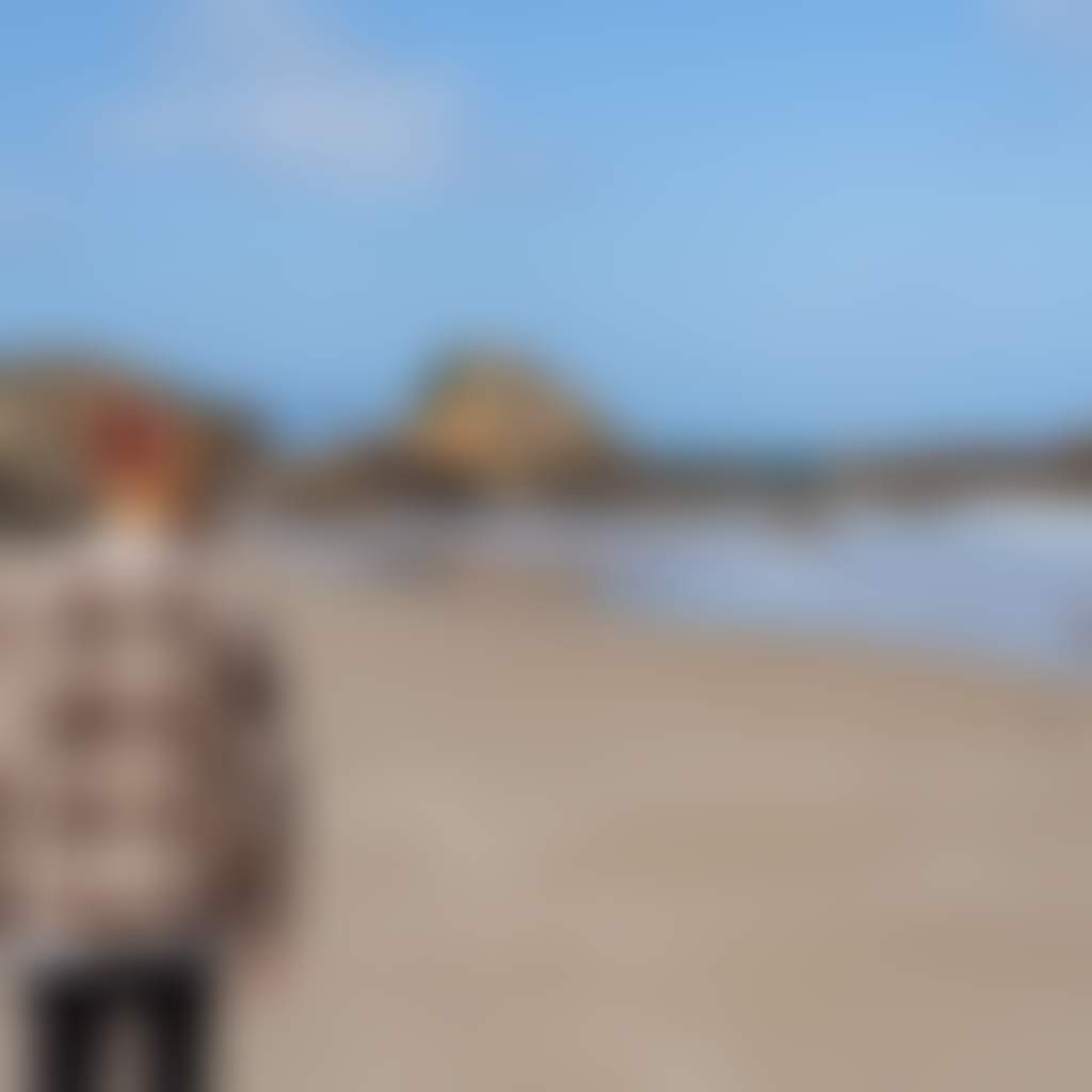 Secret Beach Mallacoota man walking on beach looking toward rock formations beanie
