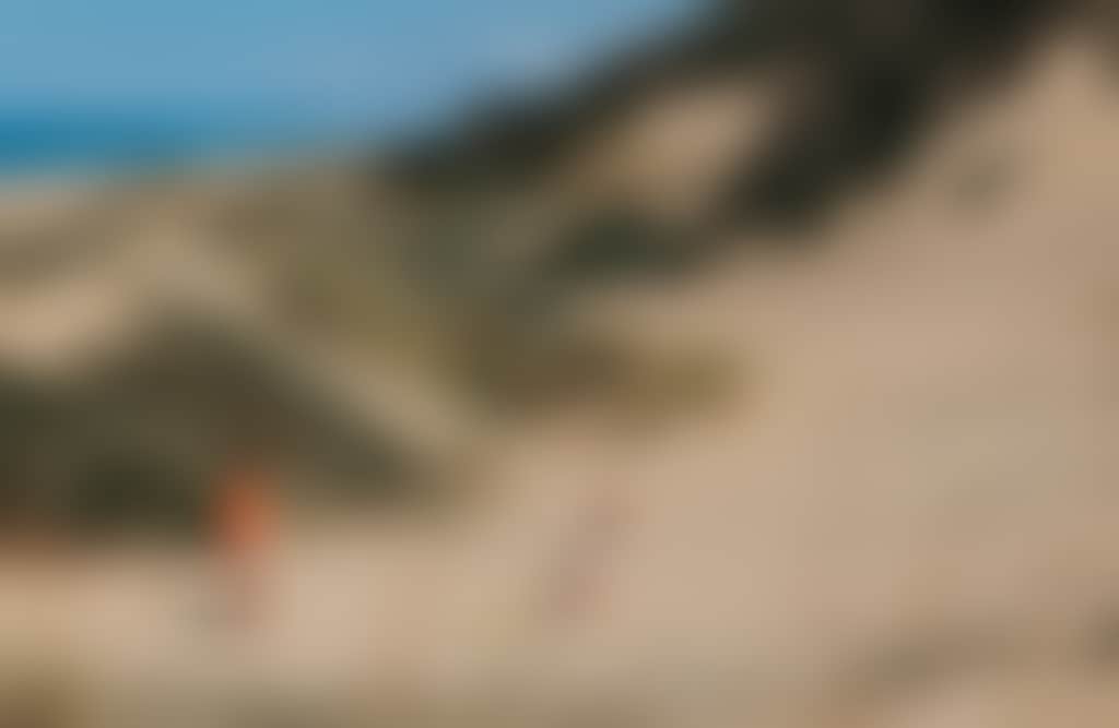 Corringle Slips Marlo family playing in sand dunes on a sunny day with ocean in background