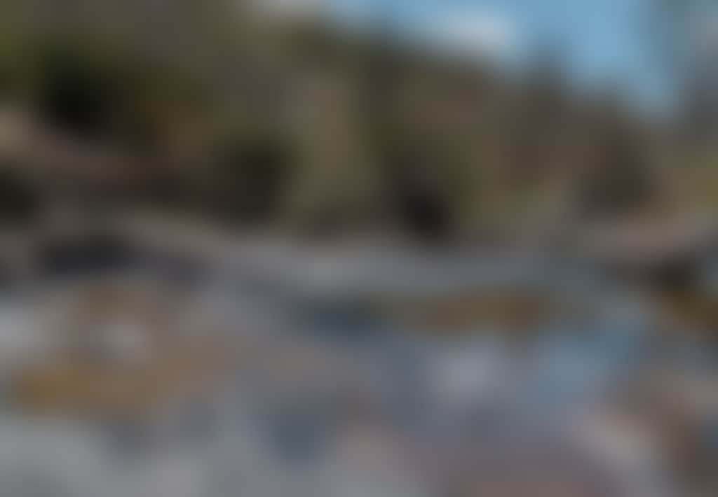 Woman sitting on rocks beside river at Little River Falls
