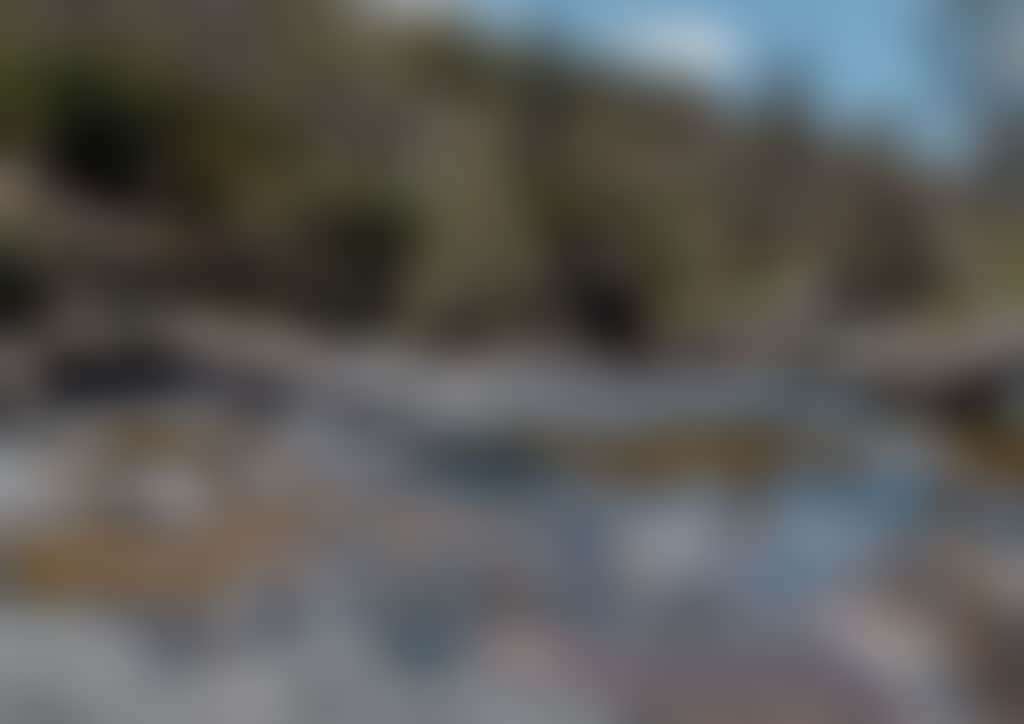 Woman sitting on rocks beside river at Little River Falls