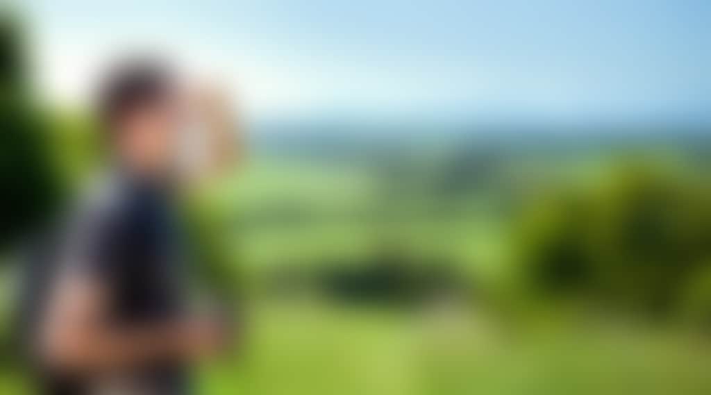 Guy with camera overlooking green hills on the Great Southern Rail Trail