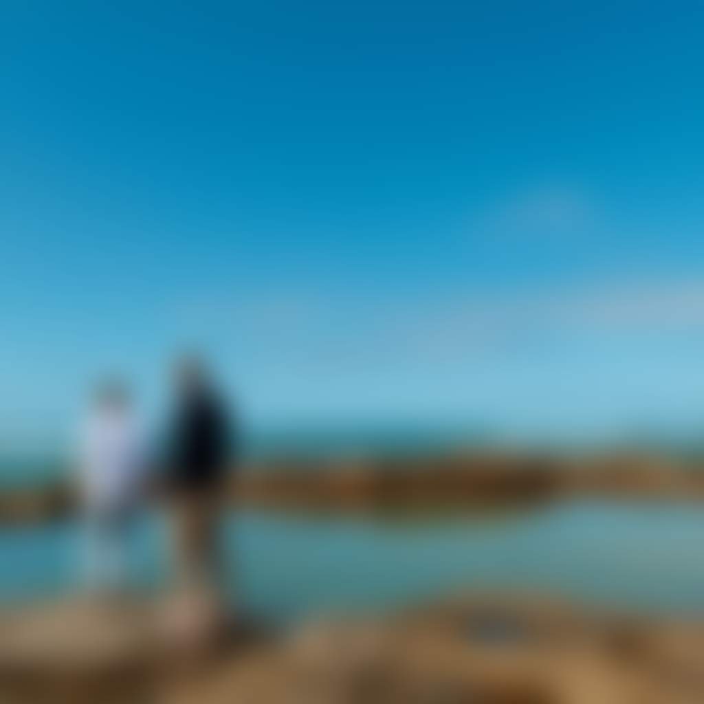 Cape Paterson Beach couple standing on edge of bright blue rockpool