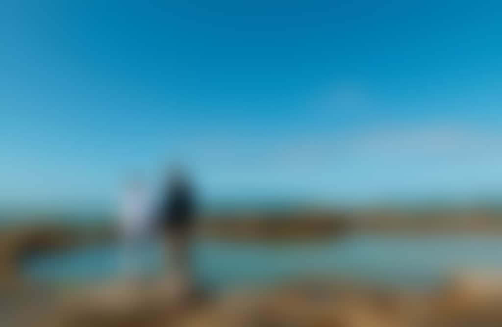 Cape Paterson Beach couple standing on edge of bright blue rockpool