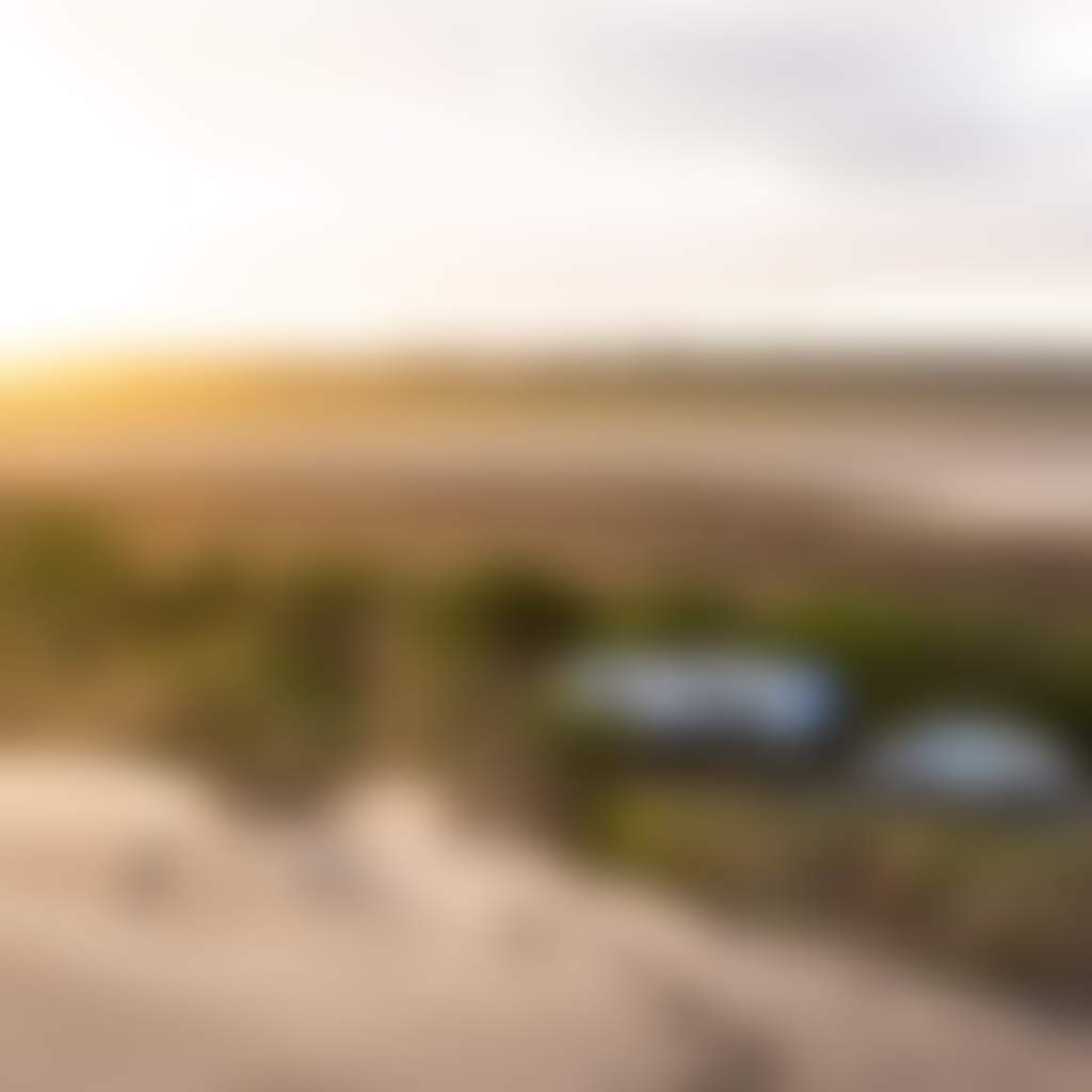 Car towing caravan with sand in foreground and lake in background