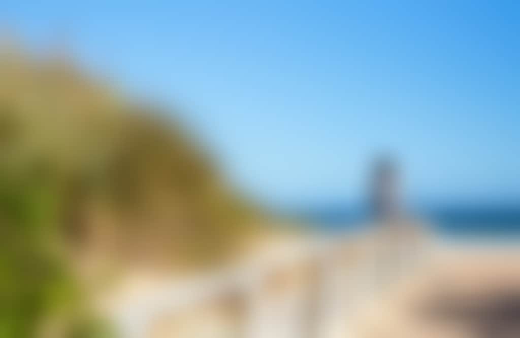 Woman sitting on the beach with grasses at Main Beach Lakes Entrance